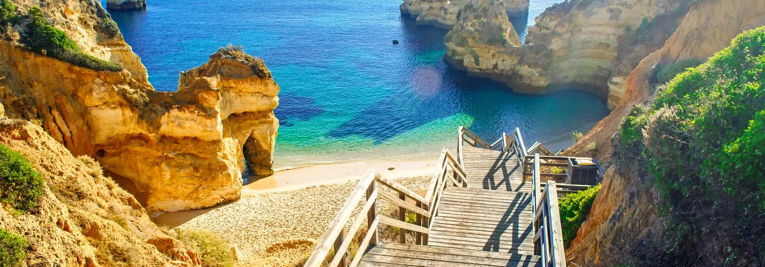 Rotsen en een lange trap naar het strand in de Algave, Portugal.